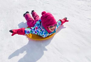 Kid sledding down a hill.