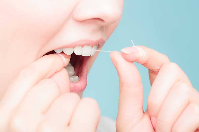 Woman practicing good oral hygiene with dental floss.