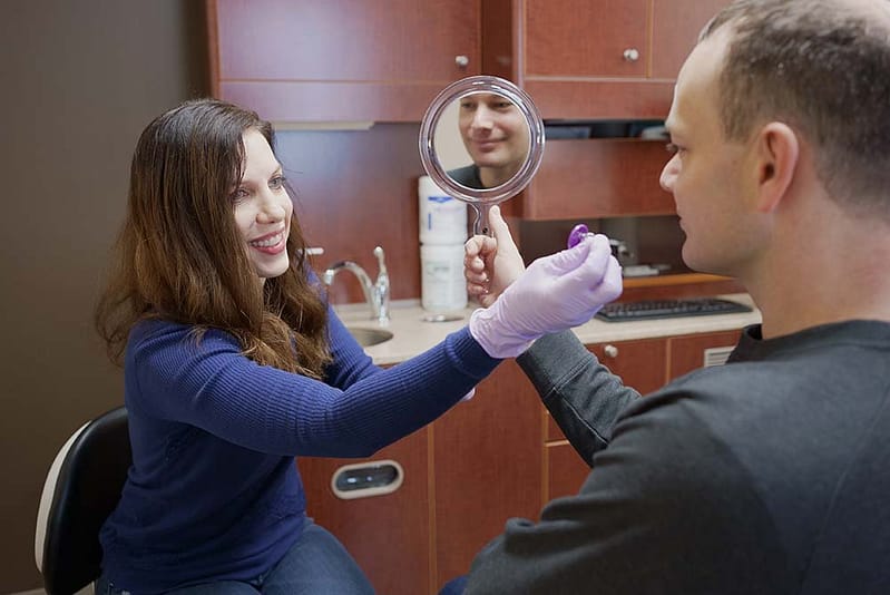 Myofunctional Therapy staff at Govani Dental working with a patient holding a mirror.