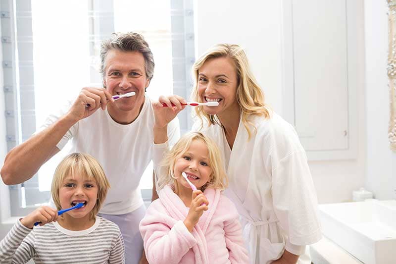 Family brushing teeth and practicing oral hygiene.